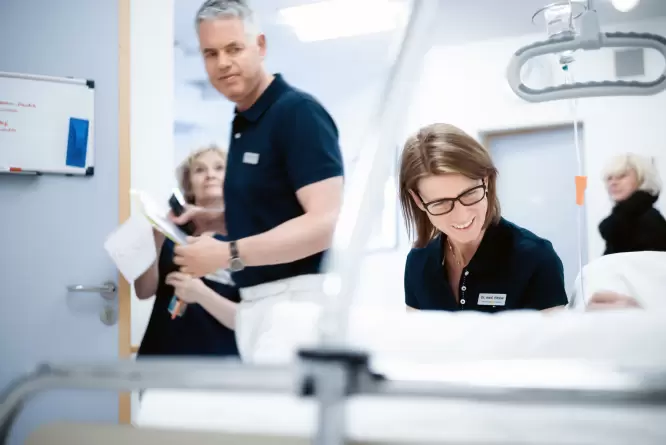 Dr. Alcock und Dr. Hesse im Gespräch mit einem Patienten bei der stationären Behandlung